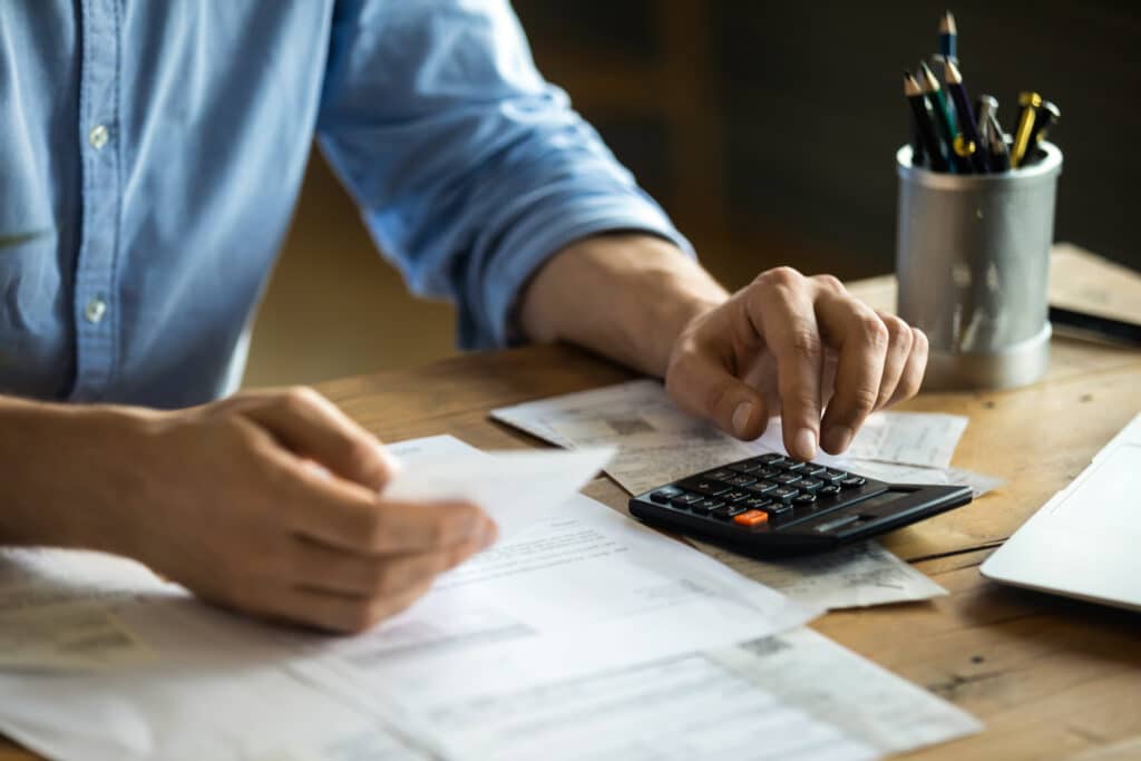 Man sitting at table using calculator calculates costs manage budget