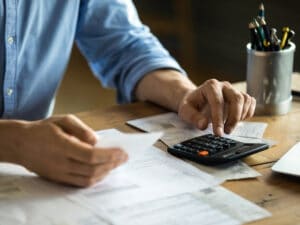 Man sitting at table using calculator calculates costs manage budget