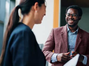 Three professionals share a light-hearted moment during a collaborative meeting, showcasing teamwork and a positive workplace atmosphere in a modern office environment.
