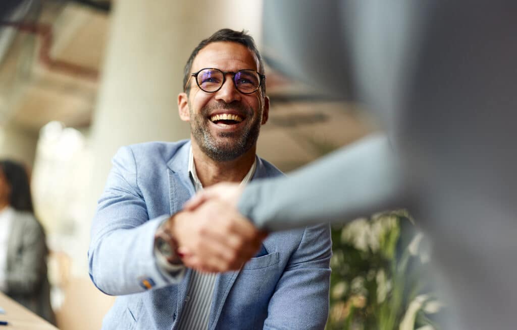 Happy male entrepreneur greeting his colleague while working in the office.
