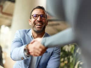 Happy male entrepreneur greeting his colleague while working in the office.
