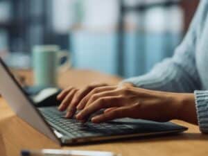 A woman typing on her laptop, only her hands and the machine visible