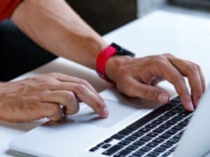 A man's hands typing on a laptop