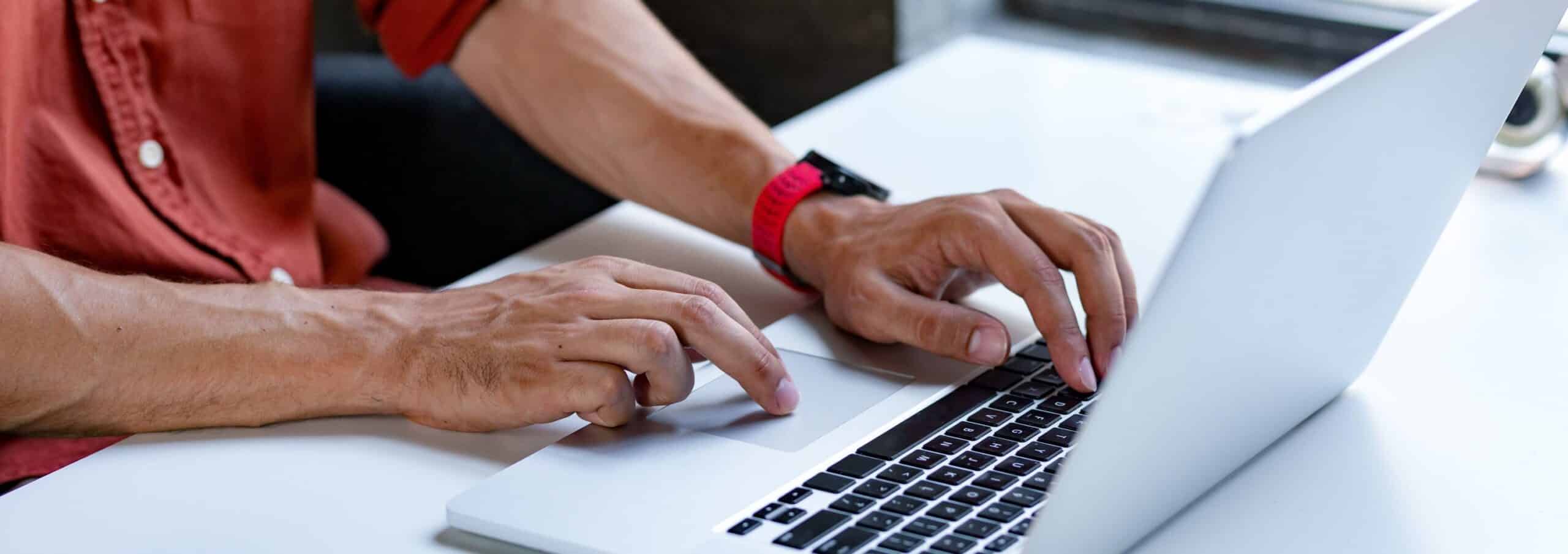 A man's hands typing on a laptop