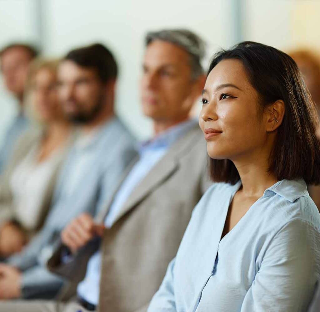 Smiling-Chinese-businesswoman-attending-a-seminar-with-her-colleagues